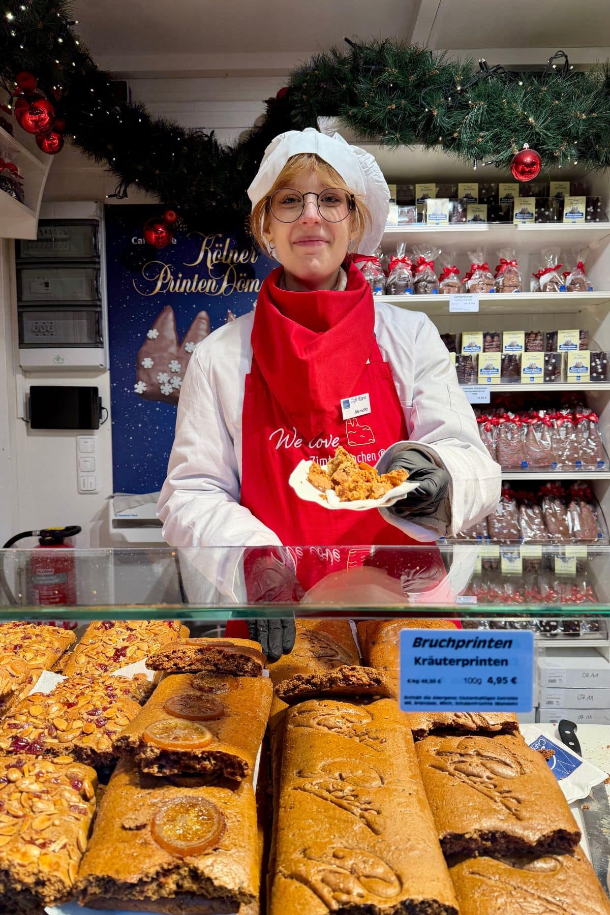 Woman in a food stall holding a napkin filled with gingerbread.