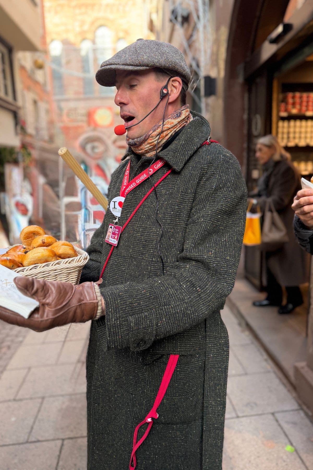 A tour guide wearing a microphone and holding a basket of pastries.