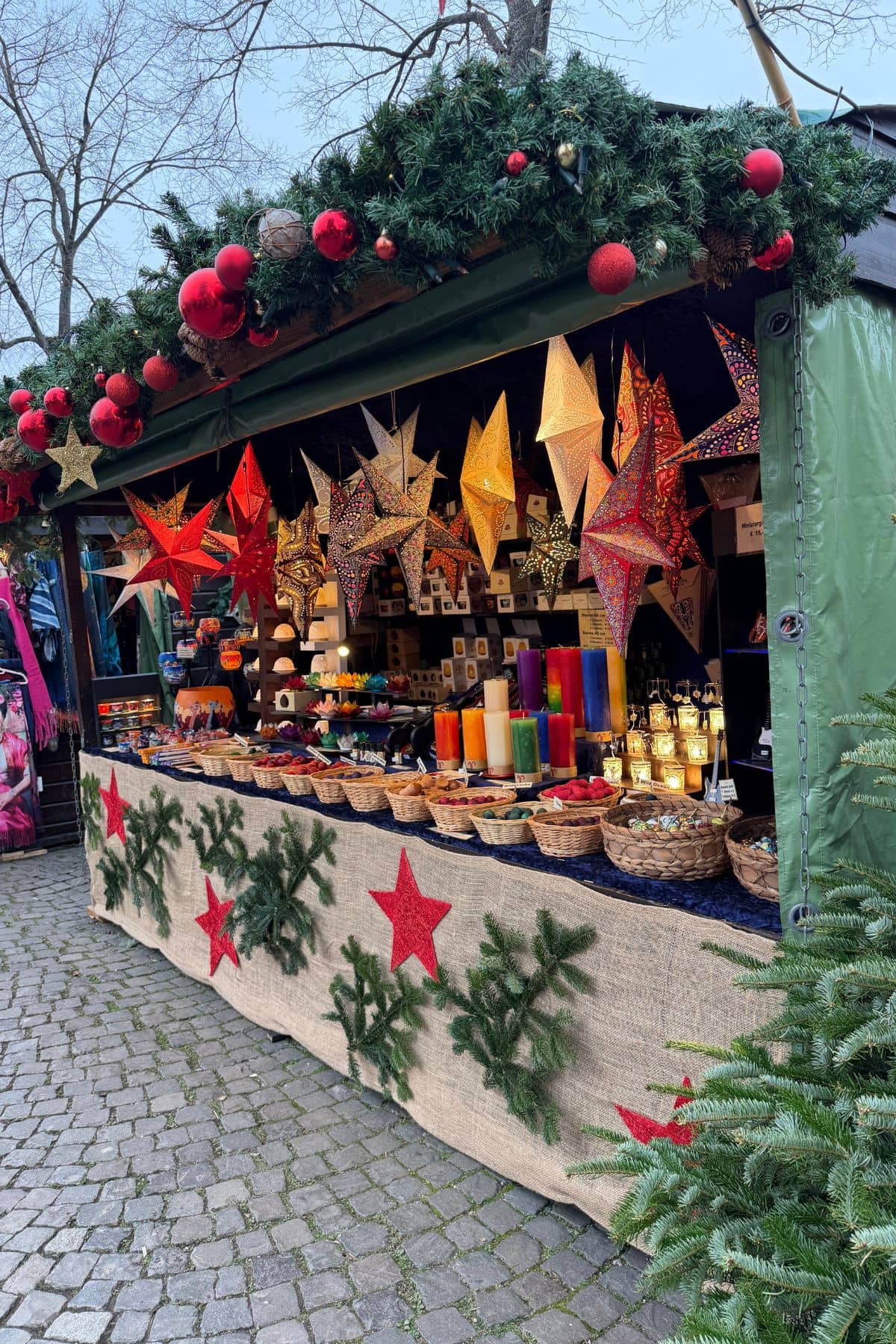 Christmas market stall with hanging stars and baskets of gift items.