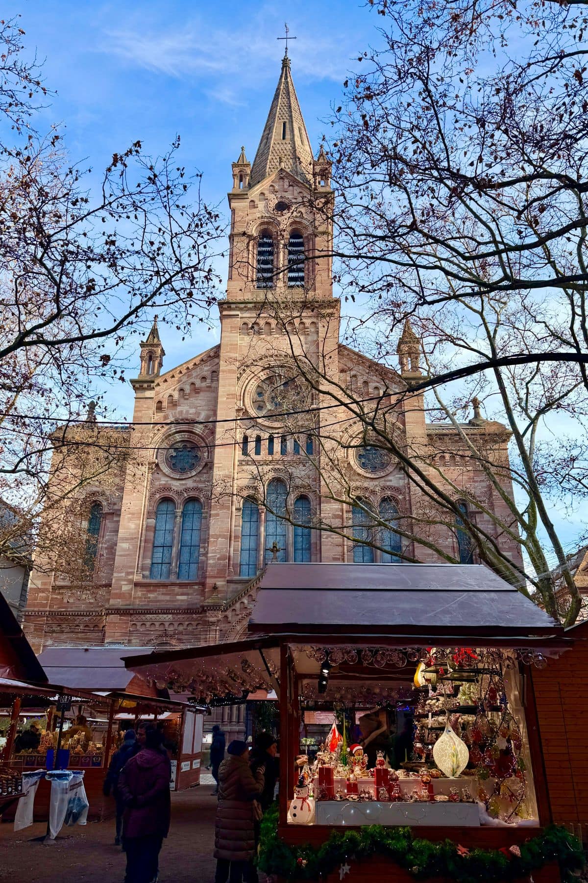 Cathedral against a blue sky with Christmas market stalls in front.