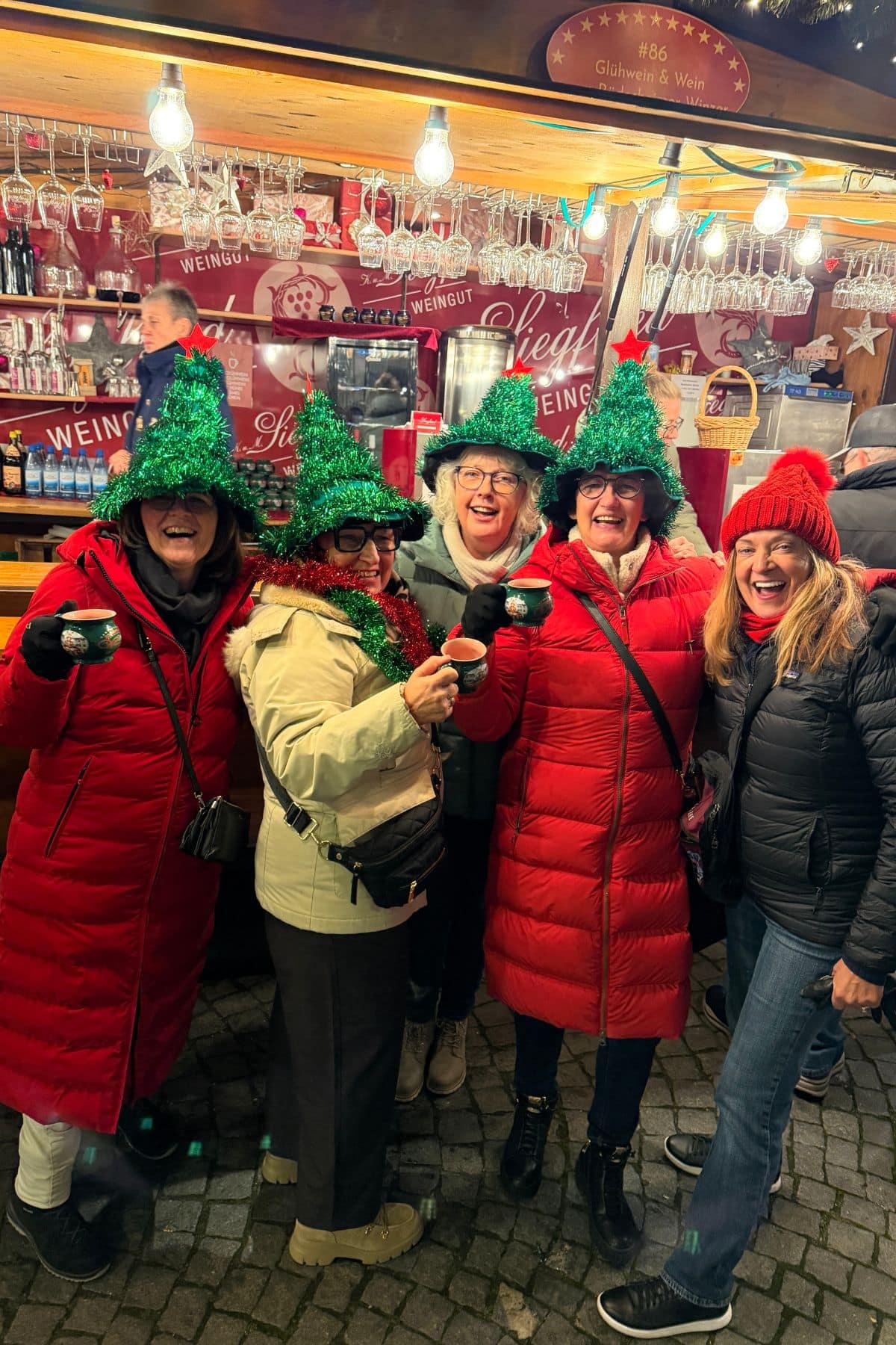Group of women drinking wine at a Christmas market stall.