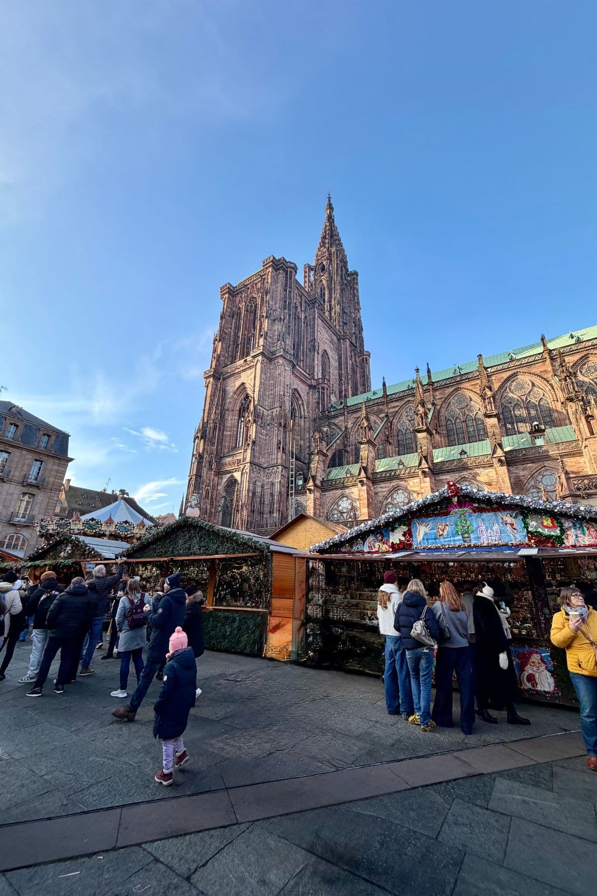 People walking around at a Christmas market with an historic cathedral in the background.