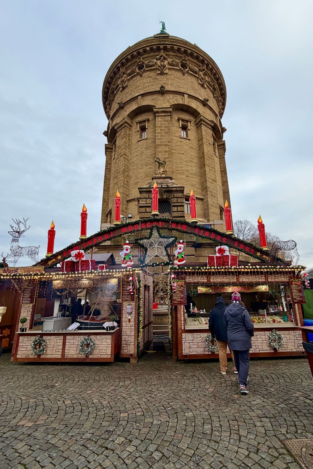 Christmas market stall in front of a historic water tower.