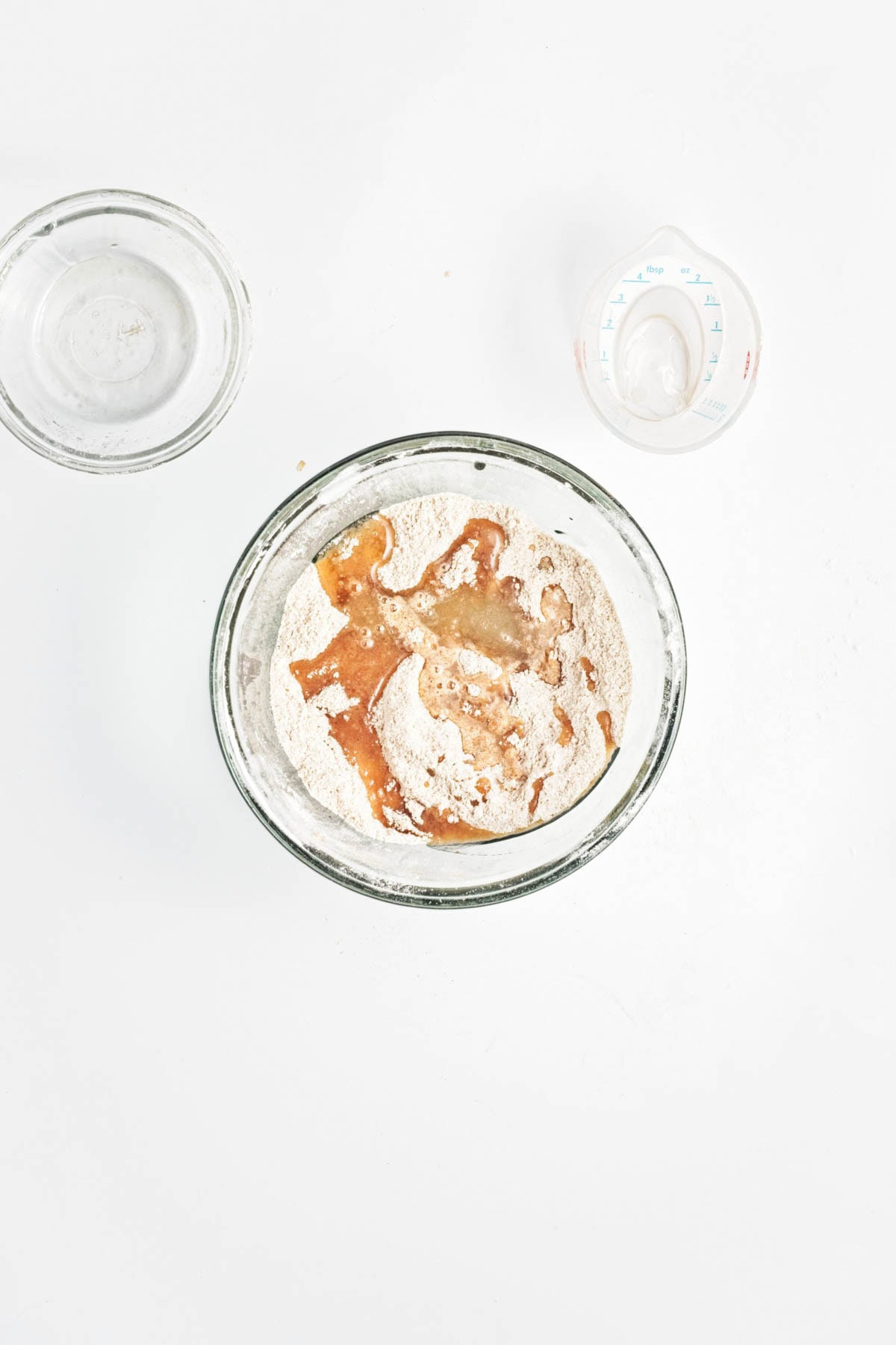 Flour, brown sugar, cinnamon, and salt with oil and water in a glass bowl.