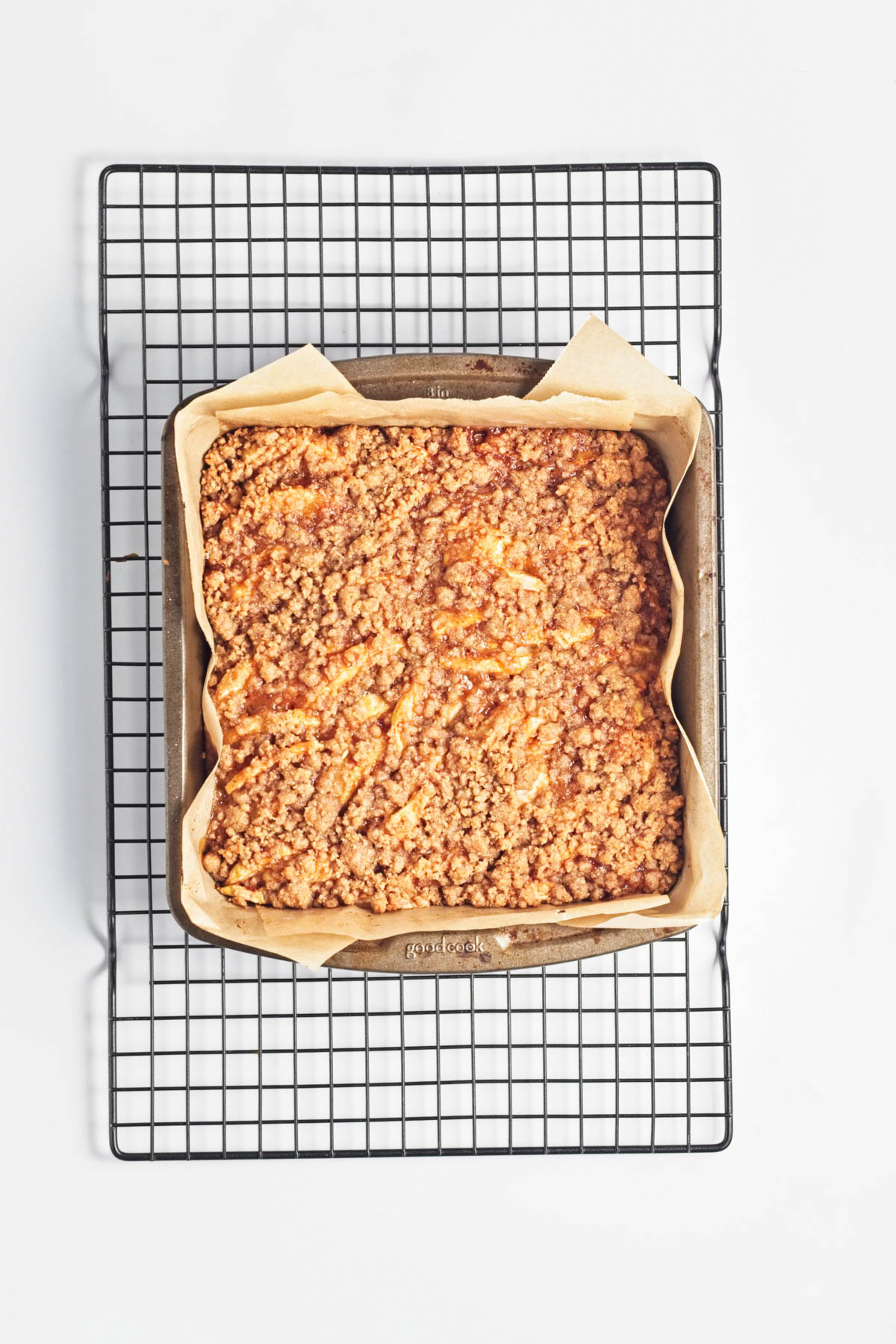 Baked apple cake with crumble on top in parchment paper-lined baking dish.