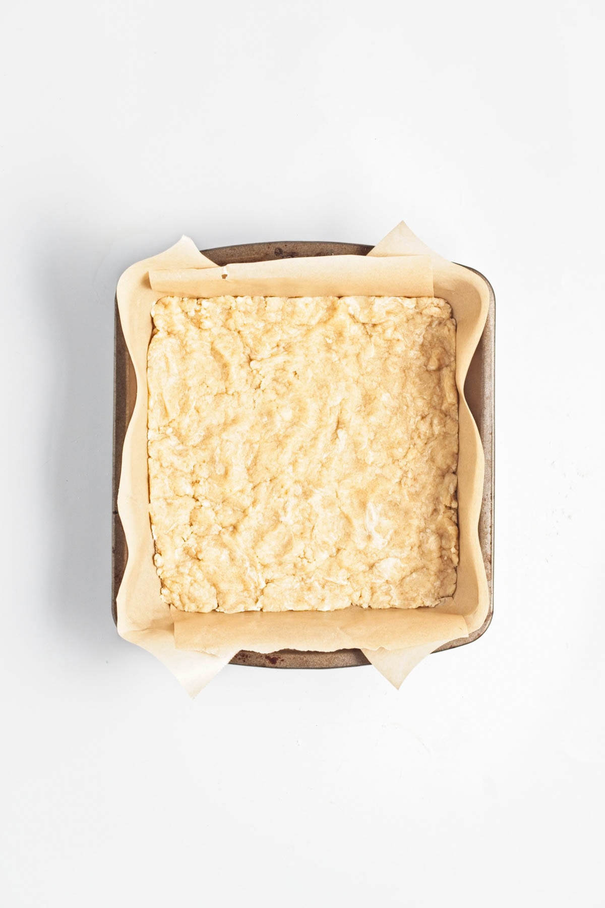 Cake batter in parchment paper in a baking dish.