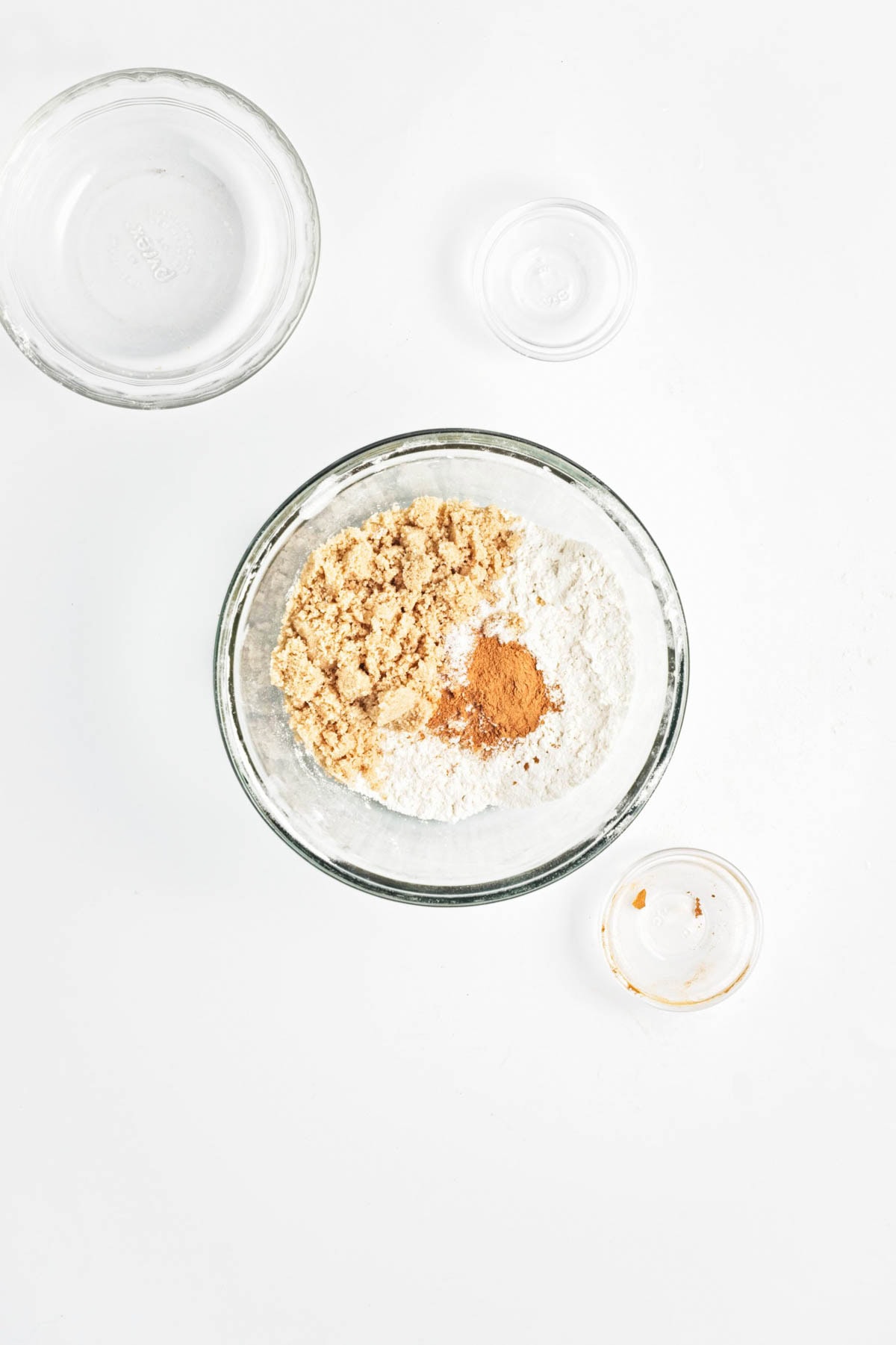 Flour, spices, and brown sugar in a glass bowl on a white counter.