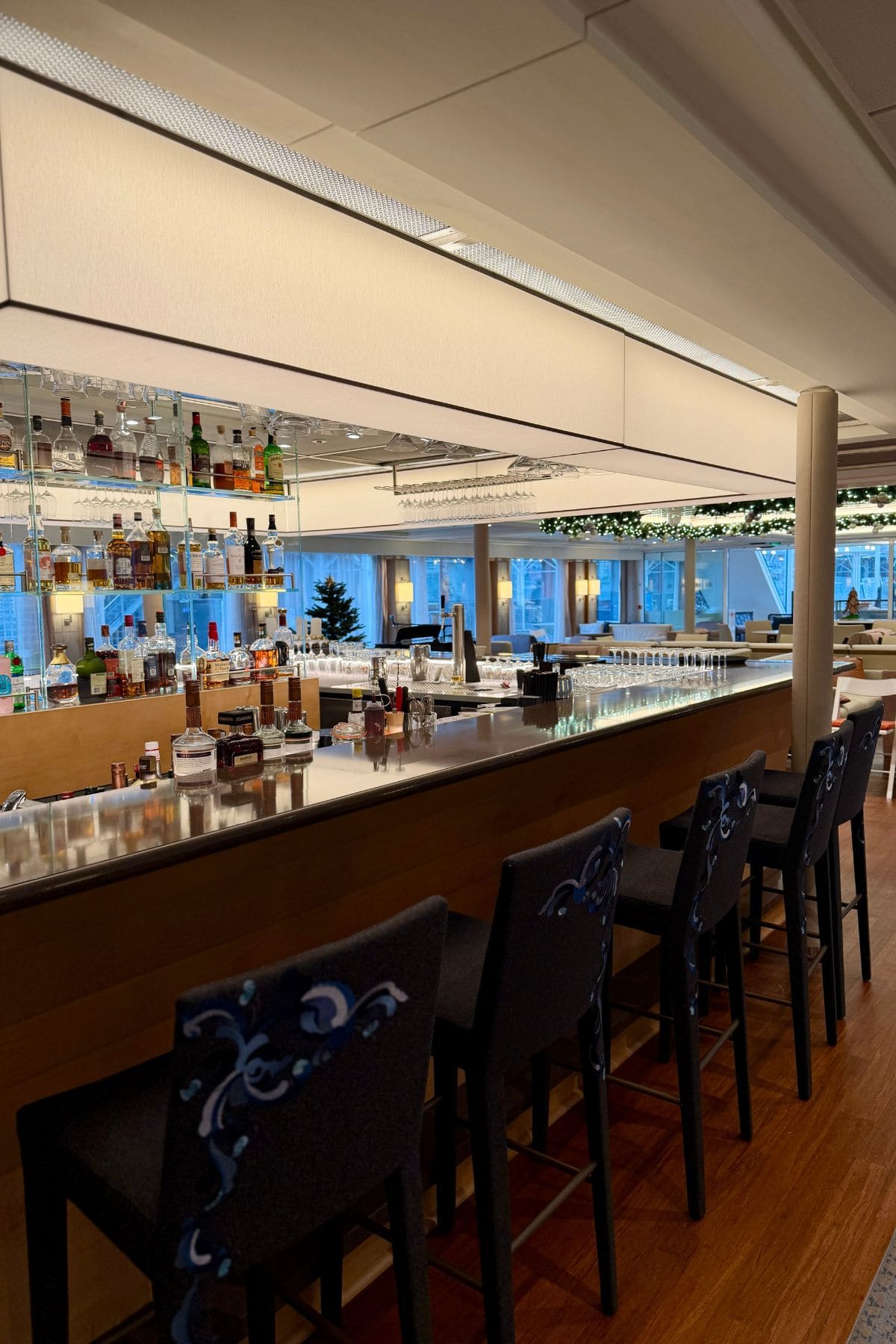 Bar with stools in a room surrounded by windows.