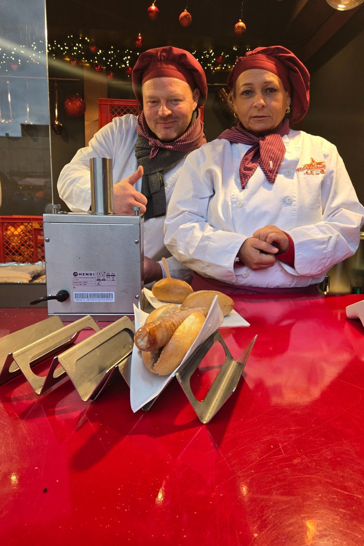 Man and woman behind the counter at a Christmas market food stall.
