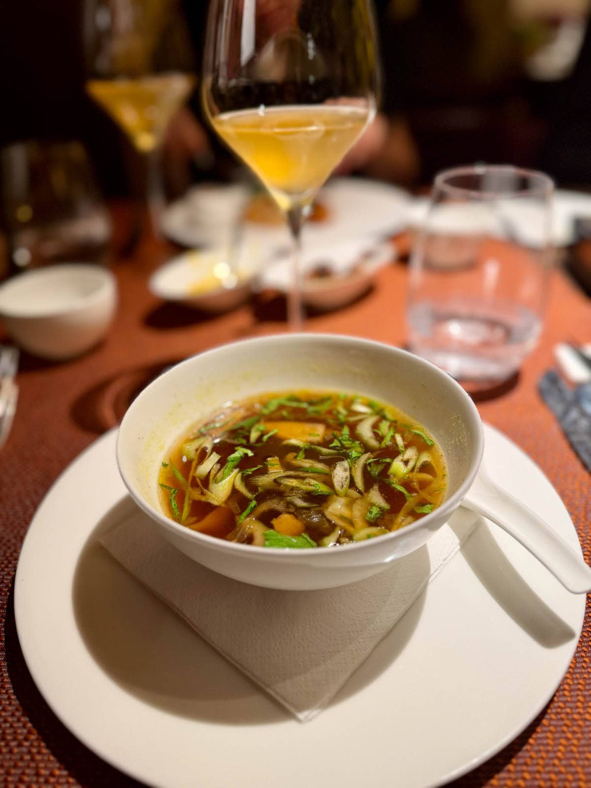 White plate with a white bowl of ramen soup.