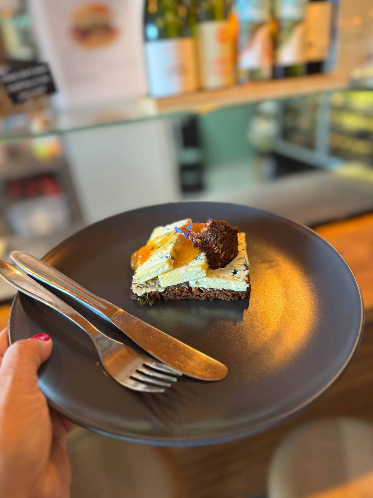 Brown bread with three pieces of blue cheese topped with a piece of gif and drizzled with honey.