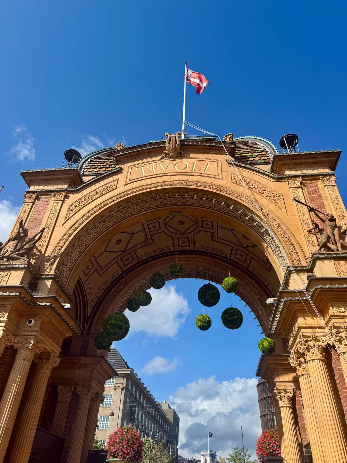 Tivoli Gardens entrance with flag on top against a blue sky.