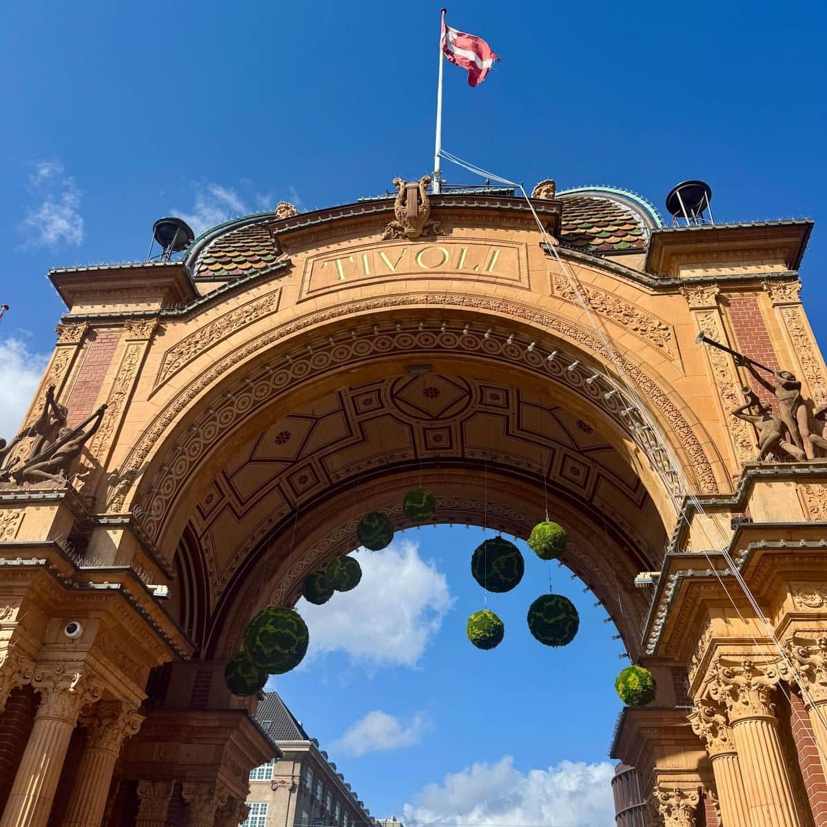 Tivoli Gardens entrance with flag on top against a blue sky.