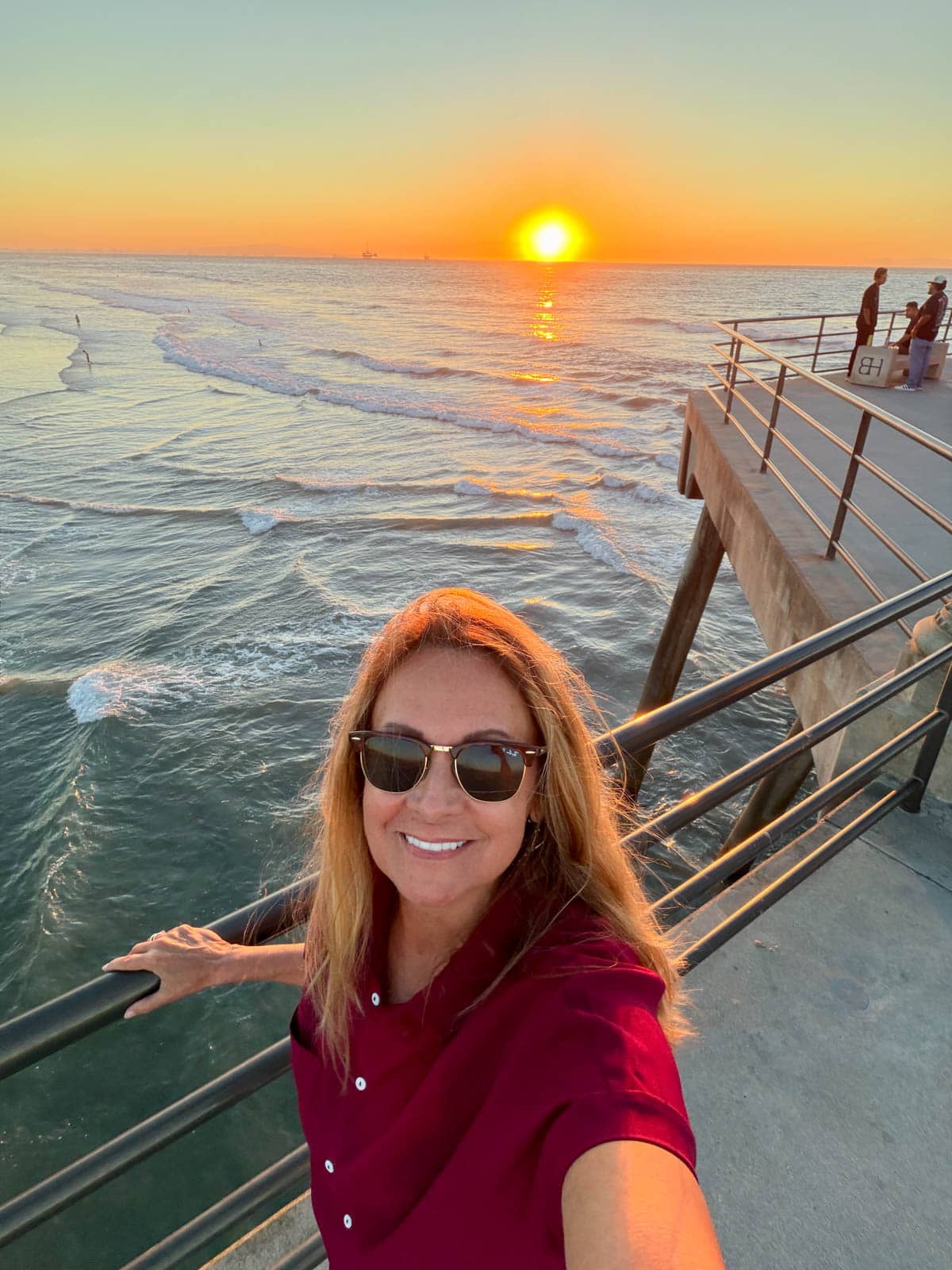 Woman smiling on pier at sunset.