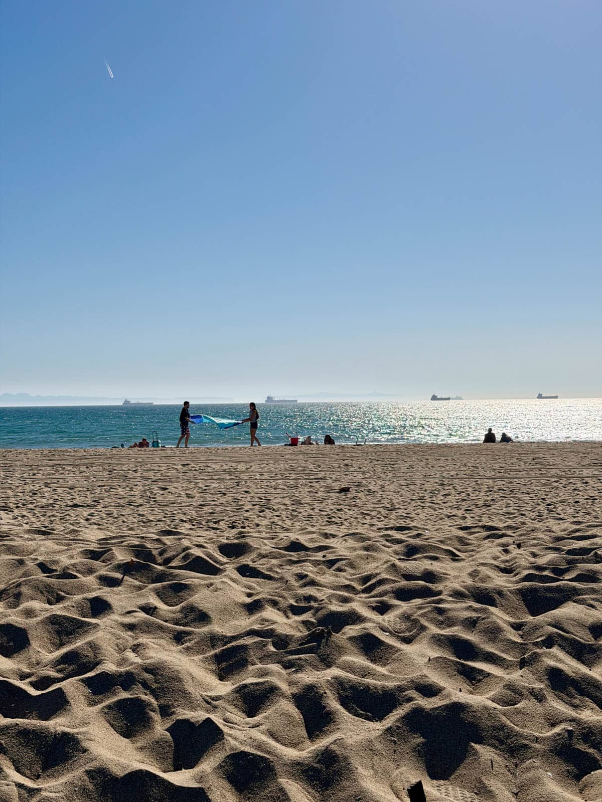 People spreading a blanket at the beach.