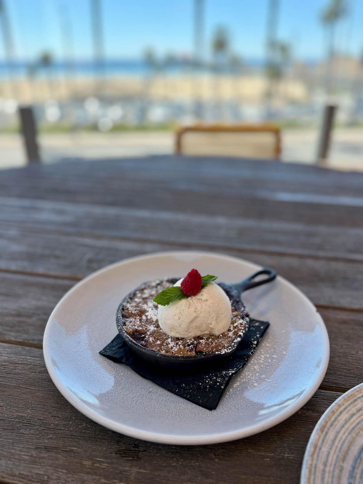 Housemade fruit cobbler with ice cream in a small black cast iron pan.