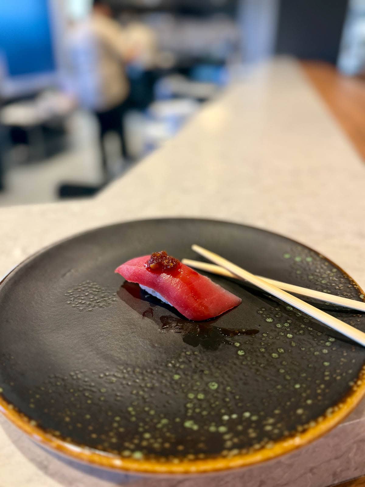 Piece of tuna sashimi with housemade sauce and garnish.