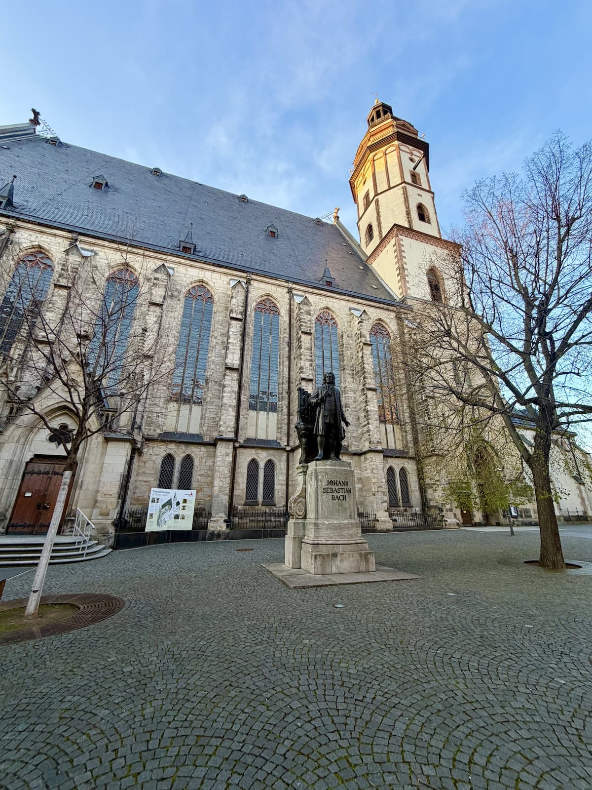 Church with a black iron statue of a Bach in front.