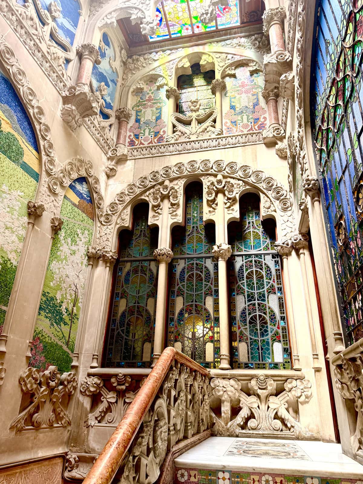 Inside an elaborate Modernist building with stained glass windows and beautiful architecture.