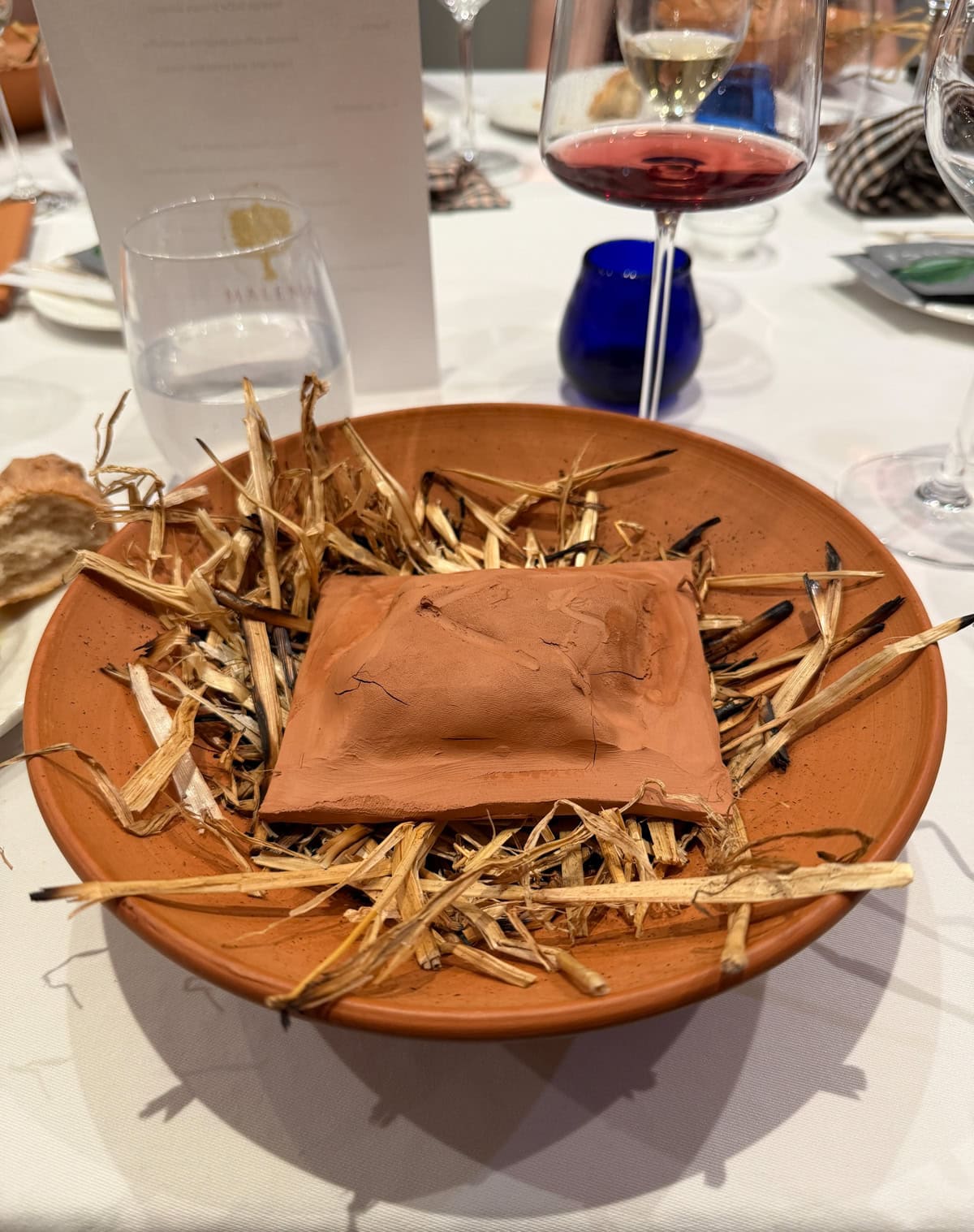 Clay packet set on straw in a clay bowl.