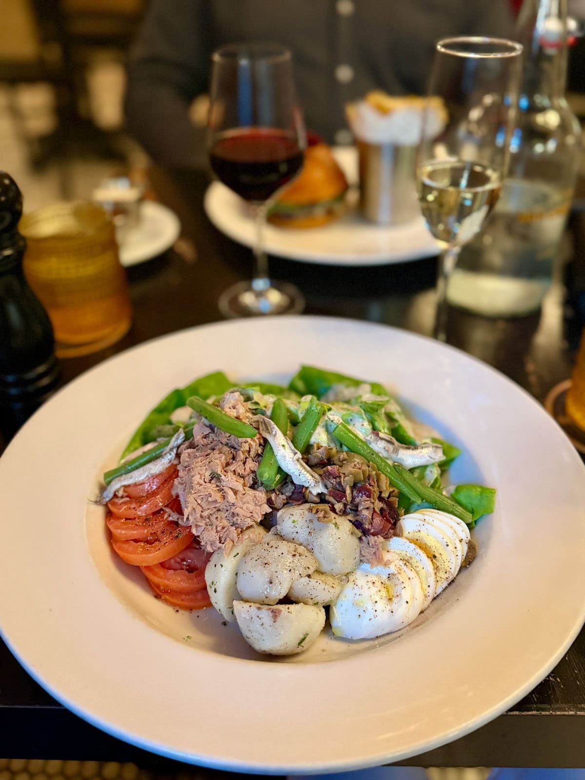 Salad with tuna, egg, green beans, potatoes, tomatoes, and olives.