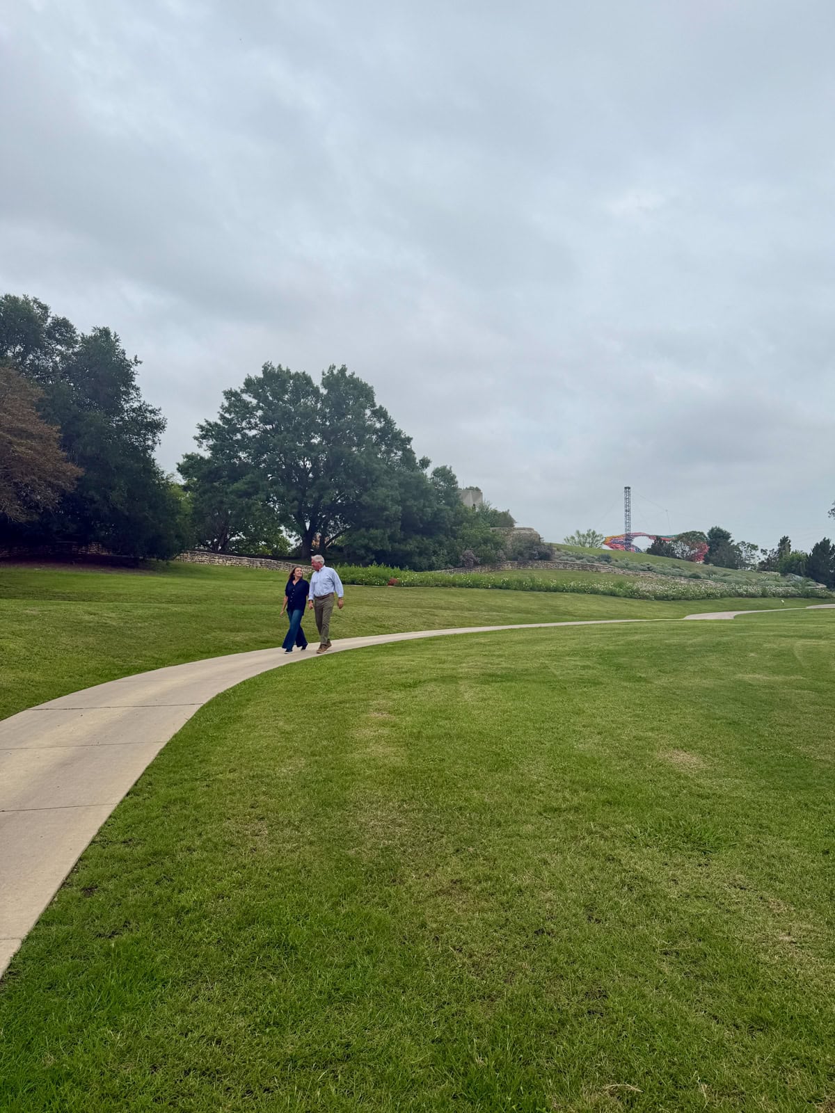 Couple walking along sidewalk at garden.