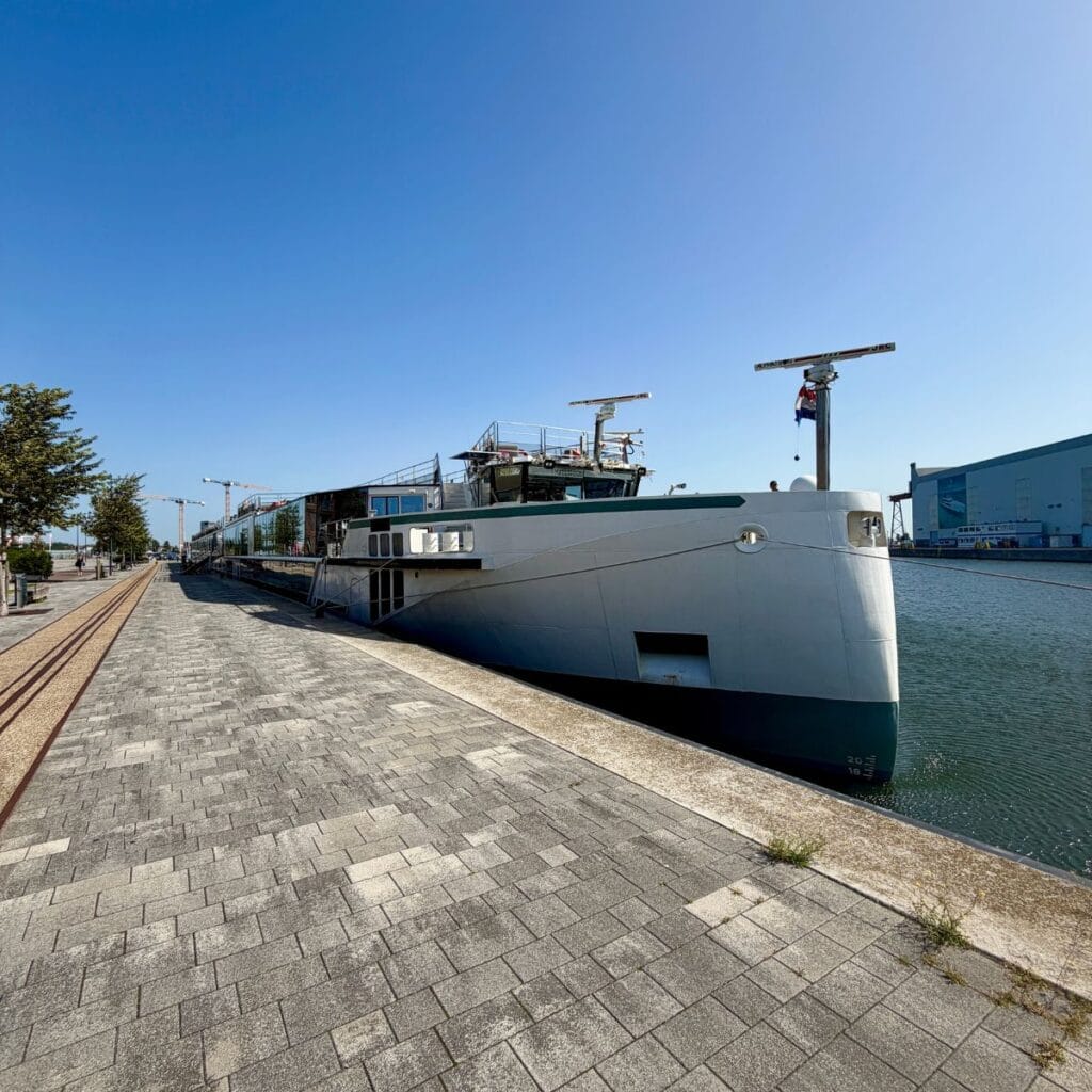 River cruise ship docked next to a brick walkway.