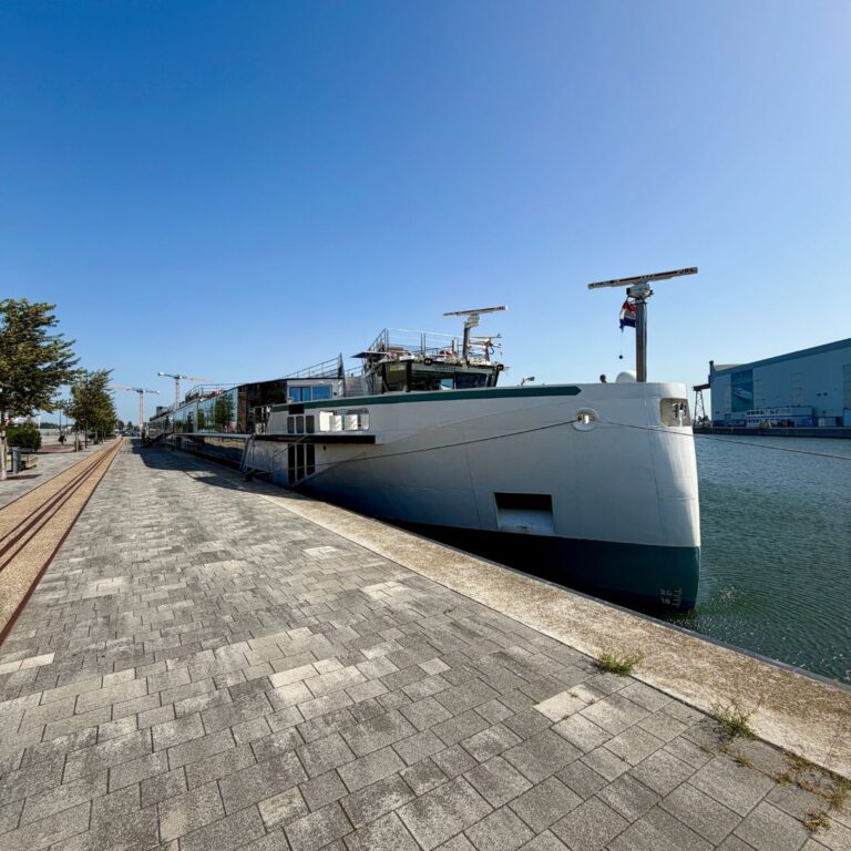 River cruise ship docked next to a brick walkway.