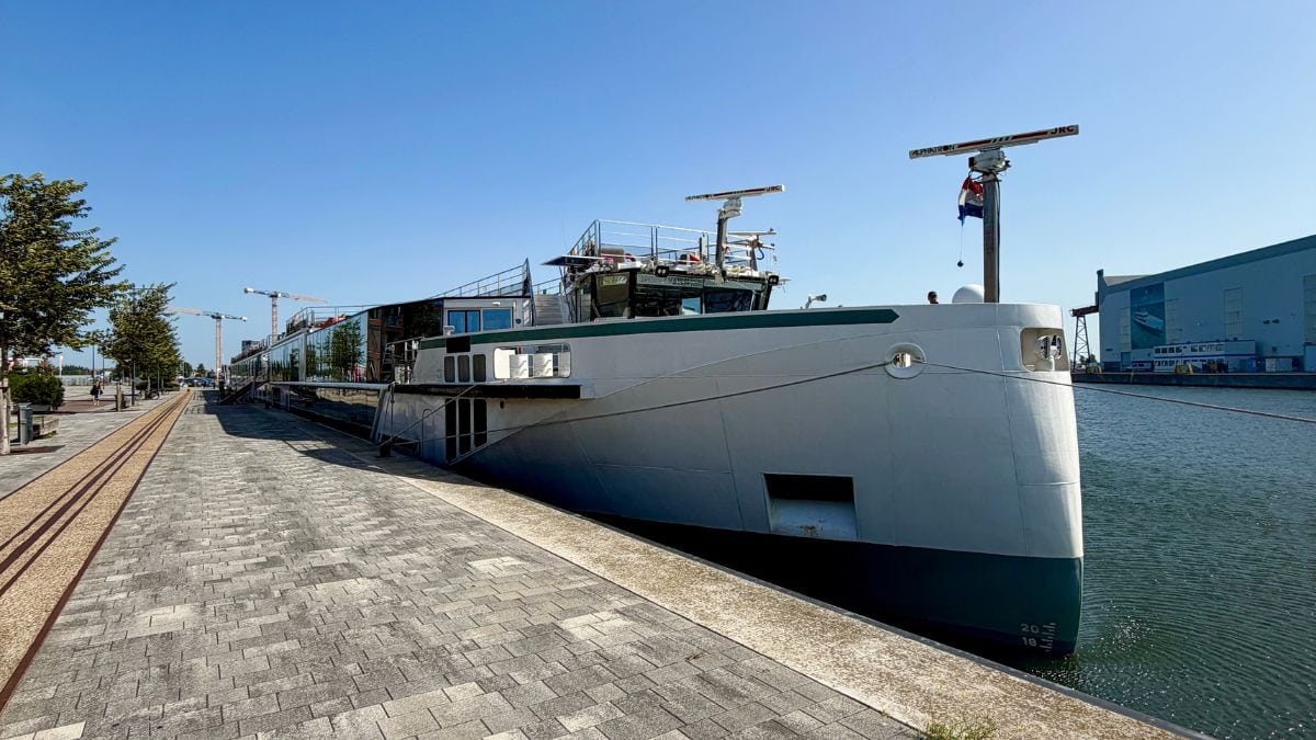 A river cruise ship docked beside a walkway.